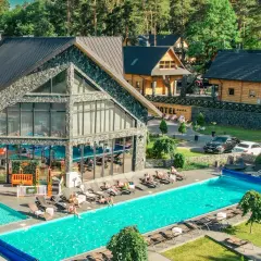Hotel Bacówka Radawa: basen, leżaki i budynki hotelowe w otoczeniu drzew.