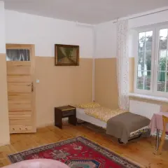 Pokój z łóżkiem, szafką nocną, drzwiami, oknem i dywanem.