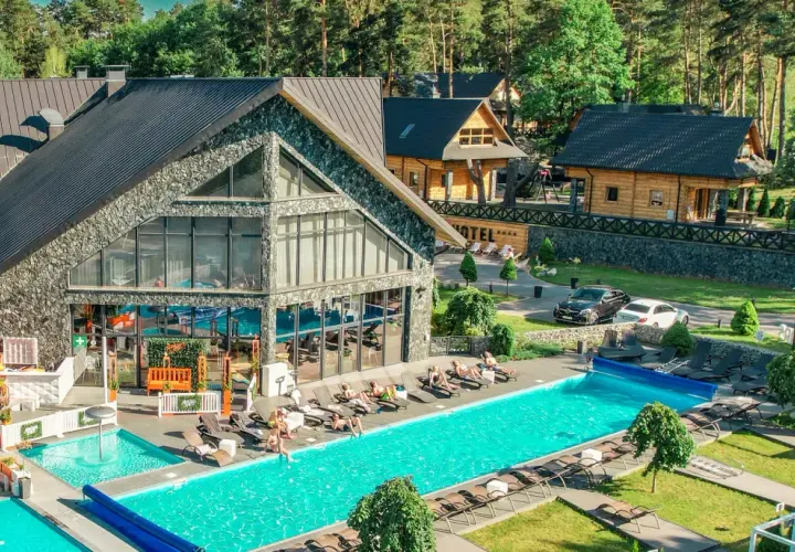 Hotel Bacówka Radawa: basen, leżaki i budynki hotelowe w otoczeniu drzew.
