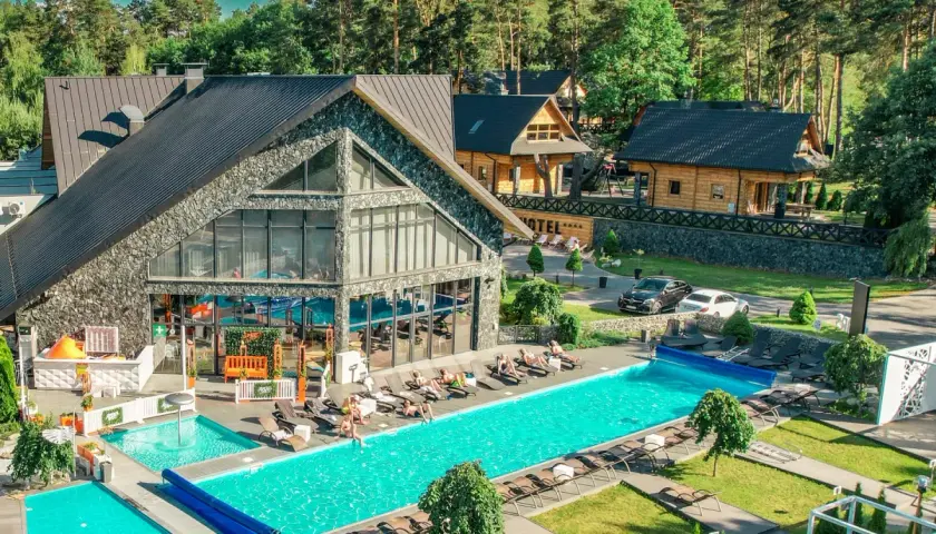 Hotel Bacówka Radawa: basen, leżaki i budynki hotelowe w otoczeniu drzew.