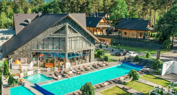 Hotel Bacówka Radawa: basen, leżaki i budynki hotelowe w otoczeniu drzew.